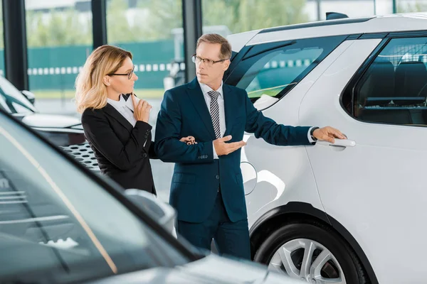 Pareja de negocios en busca de nuevo automóvil en el salón de concesionarios - foto de stock