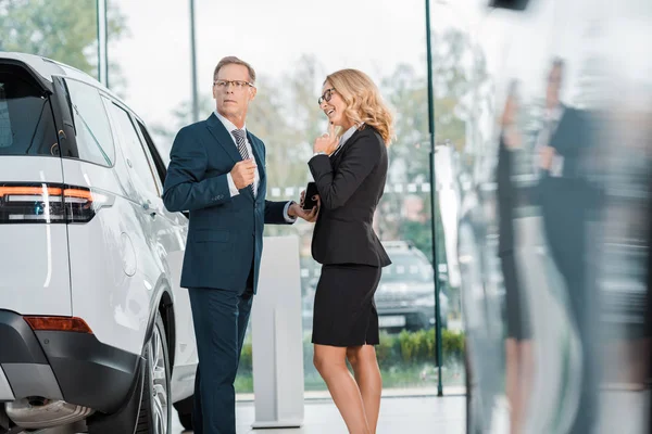 Casal de negócios à procura de novo automóvel no salão de concessionárias — Fotografia de Stock