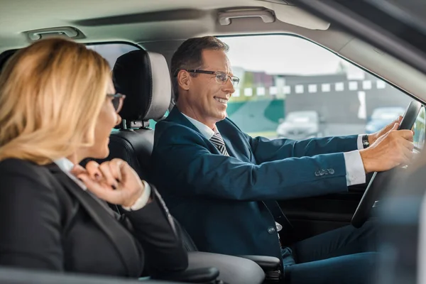 Sorridente coppia di lavoro seduto in una nuova auto per test drive — Foto stock