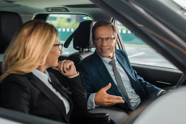 Smiling business couple sitting in new car for test drive — Stock Photo