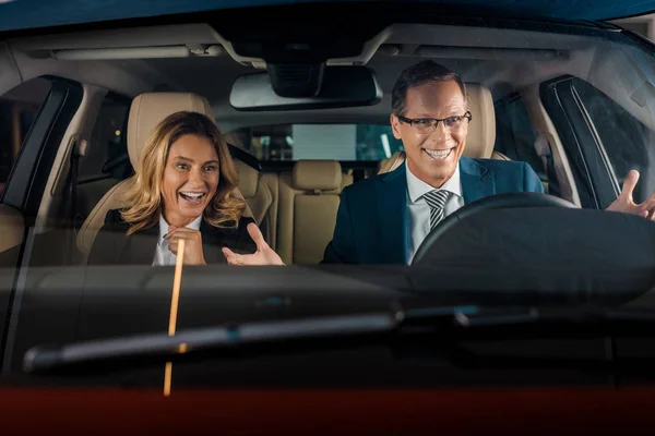 Portrait de joyeux couple d'affaires en voiture neuve pour un essai routier — Photo de stock