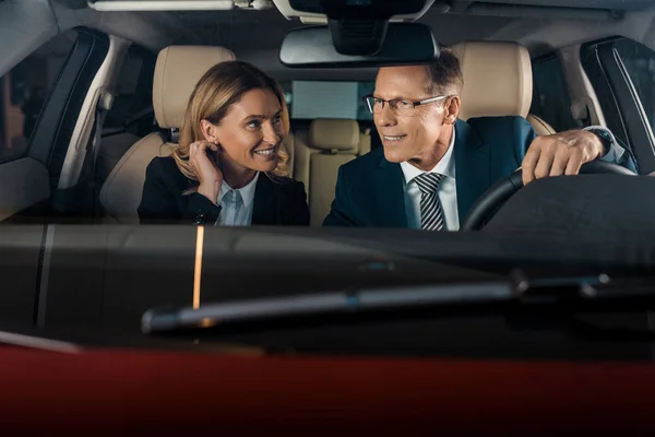 Retrato de casal de negócios sentado em carro novo para test drive — Fotografia de Stock