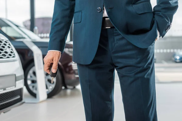 Обрізаний знімок бізнесмена з ключем від машини в дилерському салоні — стокове фото