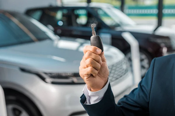 Cropped shot of businessman with car key in hand in dealership salon — Stock Photo