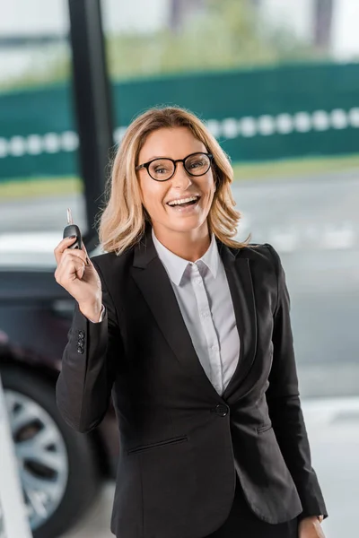 Donna d'affari sorridente che tiene la chiave dell'automobile allo showroom — Foto stock
