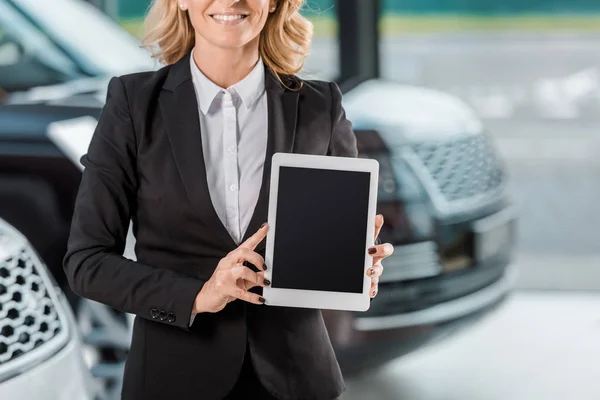 Plan recadré de concessionnaire de voiture femme tenant tablette avec écran blanc au showroom — Photo de stock