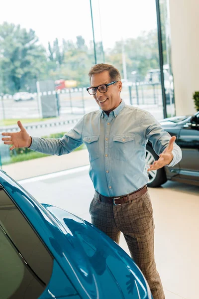Excité homme adulte regardant voiture de sport de luxe dans le showroom — Photo de stock