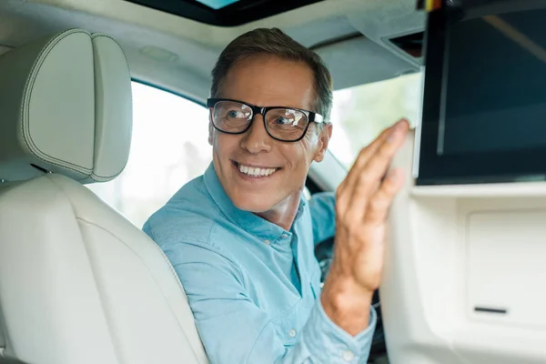 Homme adulte souriant conduisant une voiture de luxe et regardant en arrière — Photo de stock