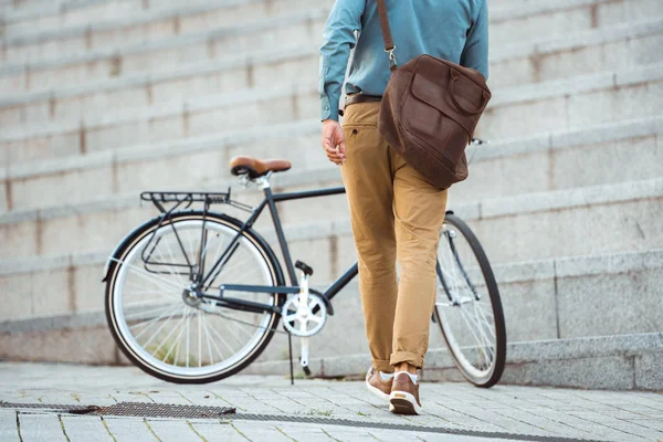 Visão traseira do homem com saco de couro andando de bicicleta estacionada na rua — Fotografia de Stock