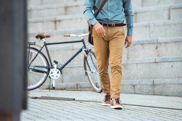 Cropped shot of stylish man walking on street, parked bicycle behind — Stock Photo