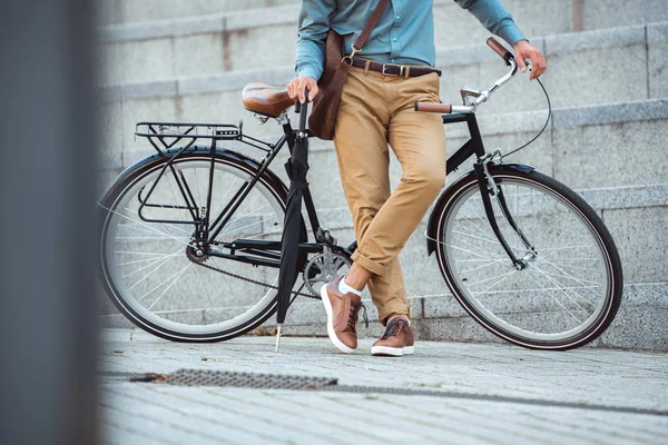 Ritagliato colpo di uomo che tiene l'ombrello e si appoggia alla bicicletta sulla strada — Foto stock