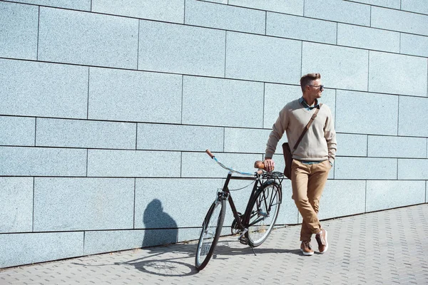 Stilvoller Mann mittleren Alters steht mit Fahrrad auf der Straße und schaut weg — Stockfoto