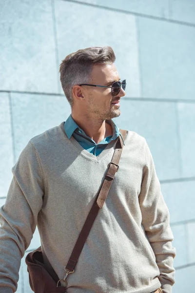 Retrato de hombre guapo y elegante de mediana edad en gafas de sol mirando hacia la calle - foto de stock