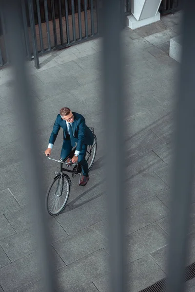 Vista ad alto angolo di uomo d'affari in abbigliamento formale in sella alla bicicletta e guardando lontano sulla strada — Foto stock