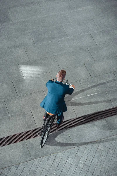 Back view of businessman in formal wear riding bicycle on street — Stock Photo