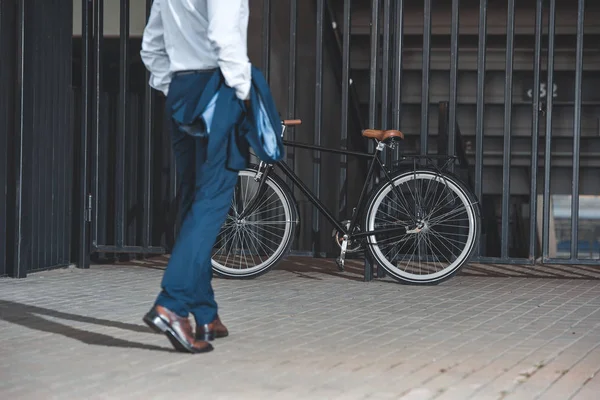 Recortado disparo de hombre de negocios en ropa formal va a bicicleta estacionado en la calle - foto de stock