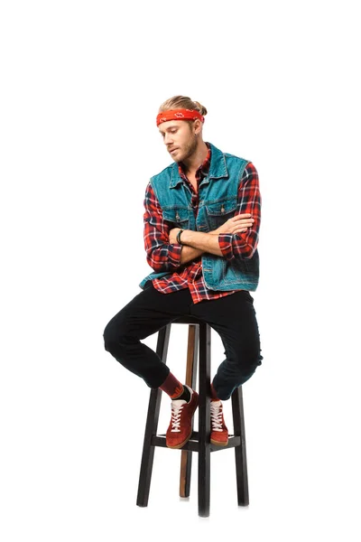 Stylish man in denim vest and red checkered shirt sitting on chair with crossed arms isolated on white — Stock Photo