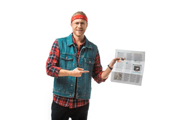 Счастливый хипстер в джинсовом жилете указывая пальцем на газету о путешествиях, изолированную на белом — стоковое фото