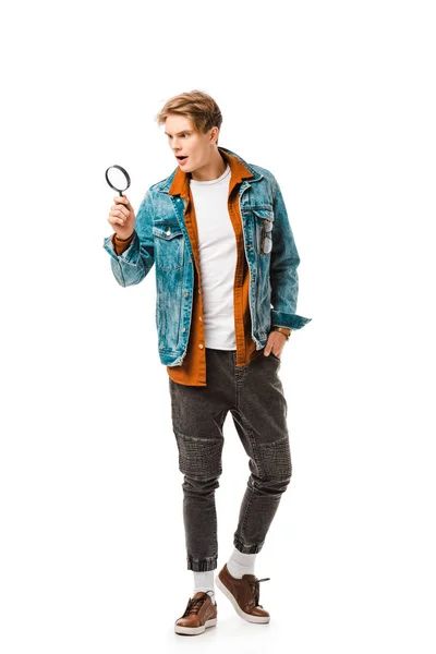 Surprised young hipster man looking at magnifying glass isolated on white — Stock Photo
