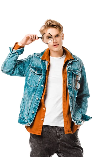 Bonito jovem hipster homem em jaqueta de ganga olhando para lupa isolado no branco — Fotografia de Stock