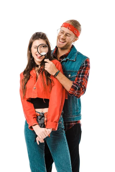 Hipster feliz se divertindo com lupa, enquanto sua namorada de pé perto isolado no branco — Fotografia de Stock