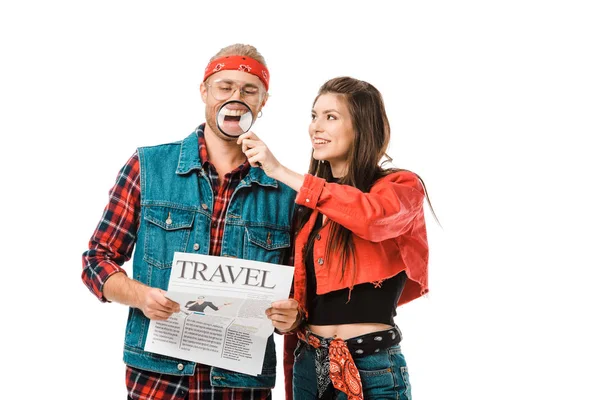 Sorridente giovane donna divertirsi con lente di ingrandimento mentre il suo fidanzato tenendo giornale di viaggio isolato su bianco — Foto stock