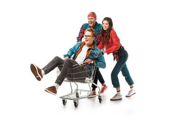 Happy young hipsters having fun with shopping cart isolated on white — Stock Photo
