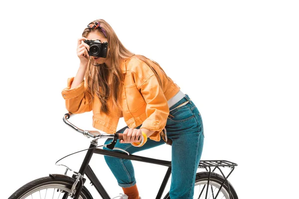 Jovem atraente hipster menina sentado na bicicleta e atirando na câmera isolada no branco — Fotografia de Stock