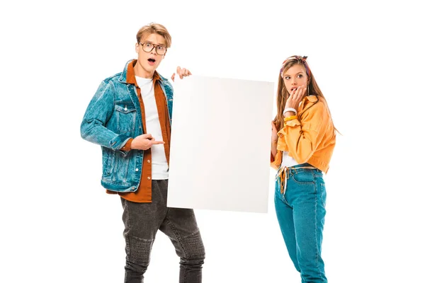 Chocado masculino hipster apontando para vazio banner enquanto sua namorada de pé perto isolado no branco — Fotografia de Stock