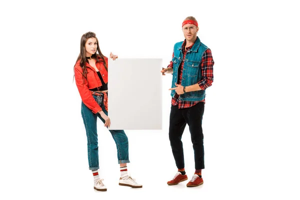 Молодий чоловік хіпстер вказує на порожній банер, а його дівчина стоїть поруч ізольовано на білому — стокове фото