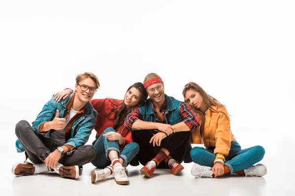 Young male hipster man in denim jacket showing thumb up while his friends sitting near isolated on white — Stock Photo