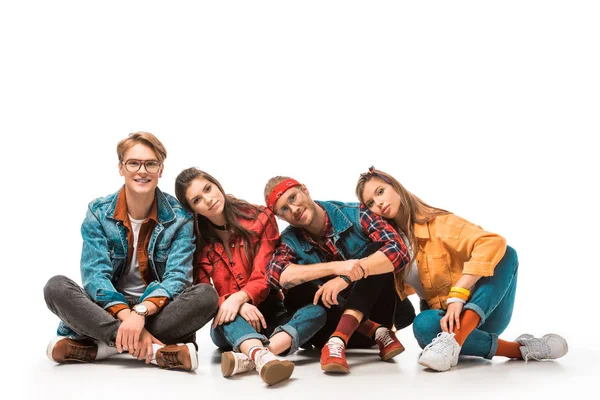 Fashionable hipster friends sitting on floor and laying heads on each other shoulders isolated on white — Stock Photo