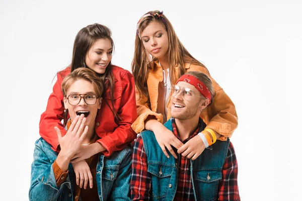 Surprised hipster covering mouth by hand and his male friend sitting near while their girlfriends standing behind isolated on white — Stock Photo