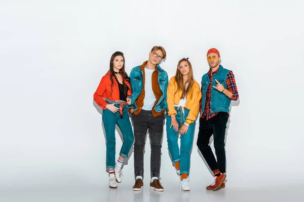 Young stylish hipsters posing together while man showing rock and roll gesture on grey — Stock Photo