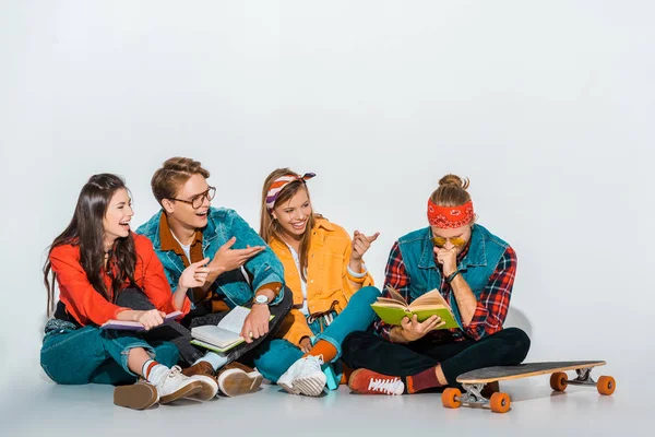 Jóvenes estudiantes riendo con longboard libros de lectura - foto de stock
