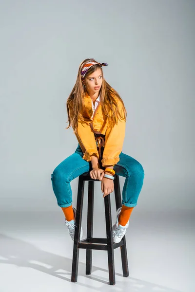 Belle fille élégante posant sur tabouret sur gris — Photo de stock