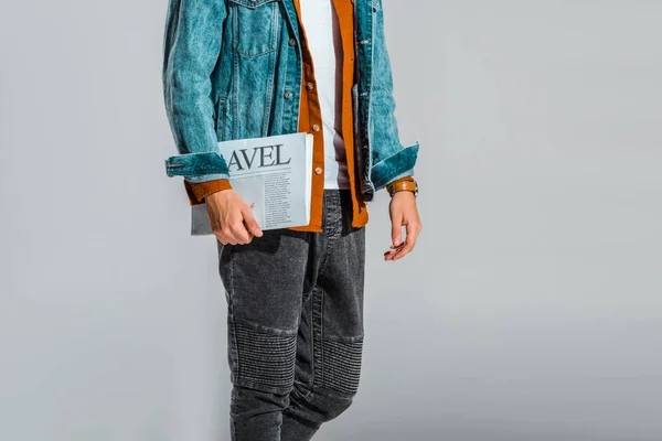 Ausgeschnittene Ansicht eines Mannes in Jeansjacke mit Reisezeitung isoliert auf grau — Stockfoto