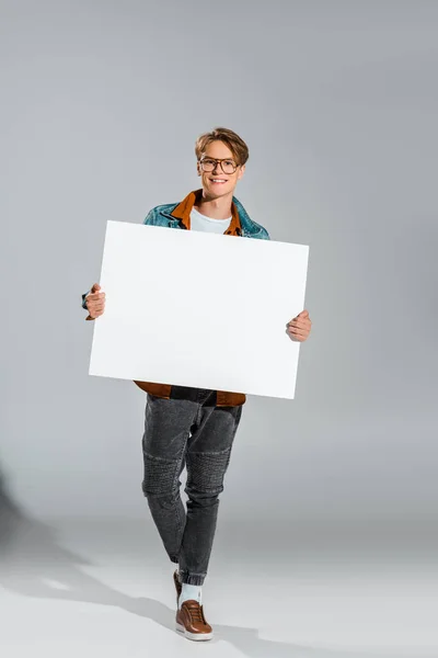 Feliz guapo hipster sosteniendo vacío tablero en gris — Stock Photo