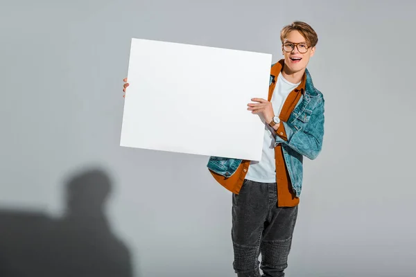 Hipster maschio eccitato con cartello vuoto sul grigio — Foto stock