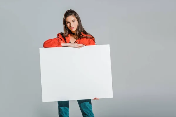 Beautiful girl holding blank placard isolated on grey — Stock Photo