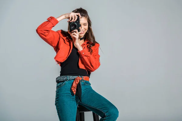 Lächelndes Mädchen, das Foto vor der Kamera macht, isoliert auf grau — Stockfoto