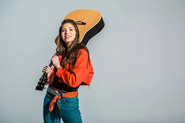 Belle fille gaie posant avec guitare acoustique isolé sur gris — Photo de stock