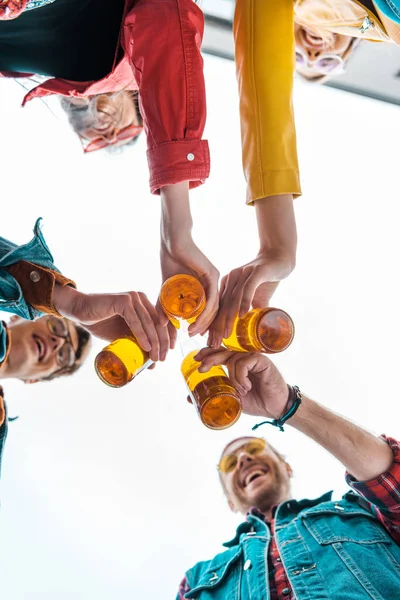 Вид снизу на молодых друзей, звонящих вместе с пивными бутылками — стоковое фото