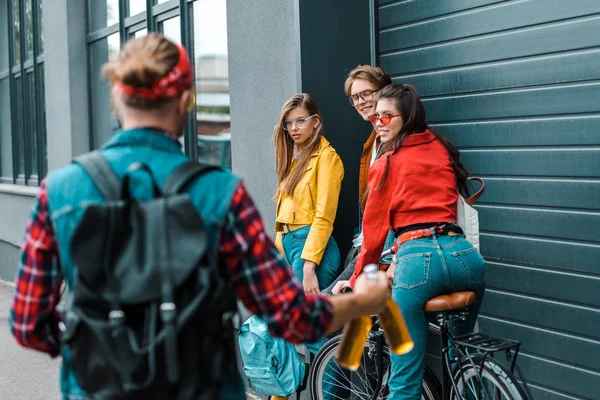 Happy hipster brought beer bottles for young friends on street with bike — Stock Photo