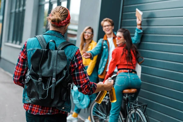 Stylish hipster brought bottles of beer for happy friends on street with bicycle — Stock Photo