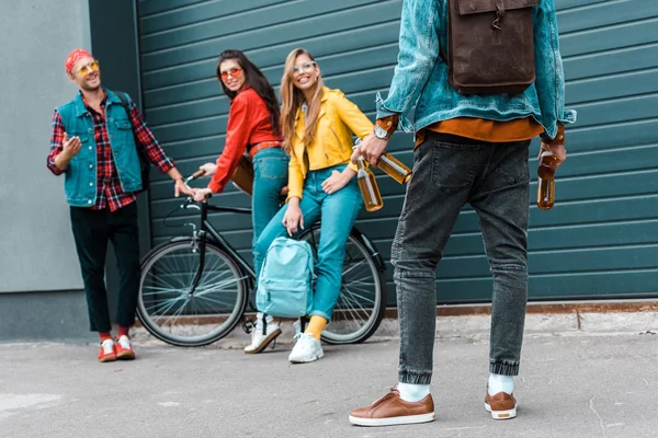 Jovem hipster trouxe garrafas de cerveja para amigos felizes na rua com bicicleta — Fotografia de Stock