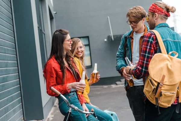 Happy friends with bicycle drinking beer from bottles on street — Stock Photo