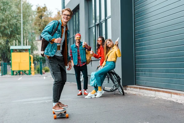 Young hipsters with longboard and bike having fun on street — Stock Photo