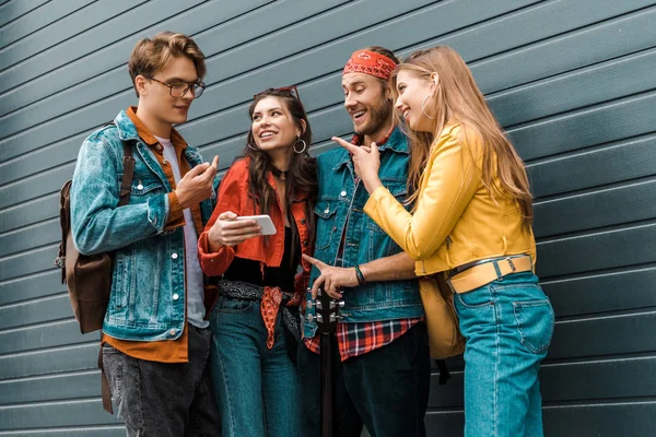 Jóvenes hipsters felices usando el teléfono inteligente juntos en la calle - foto de stock