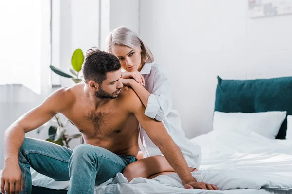 Attractive young couple sitting on bed together — Stock Photo